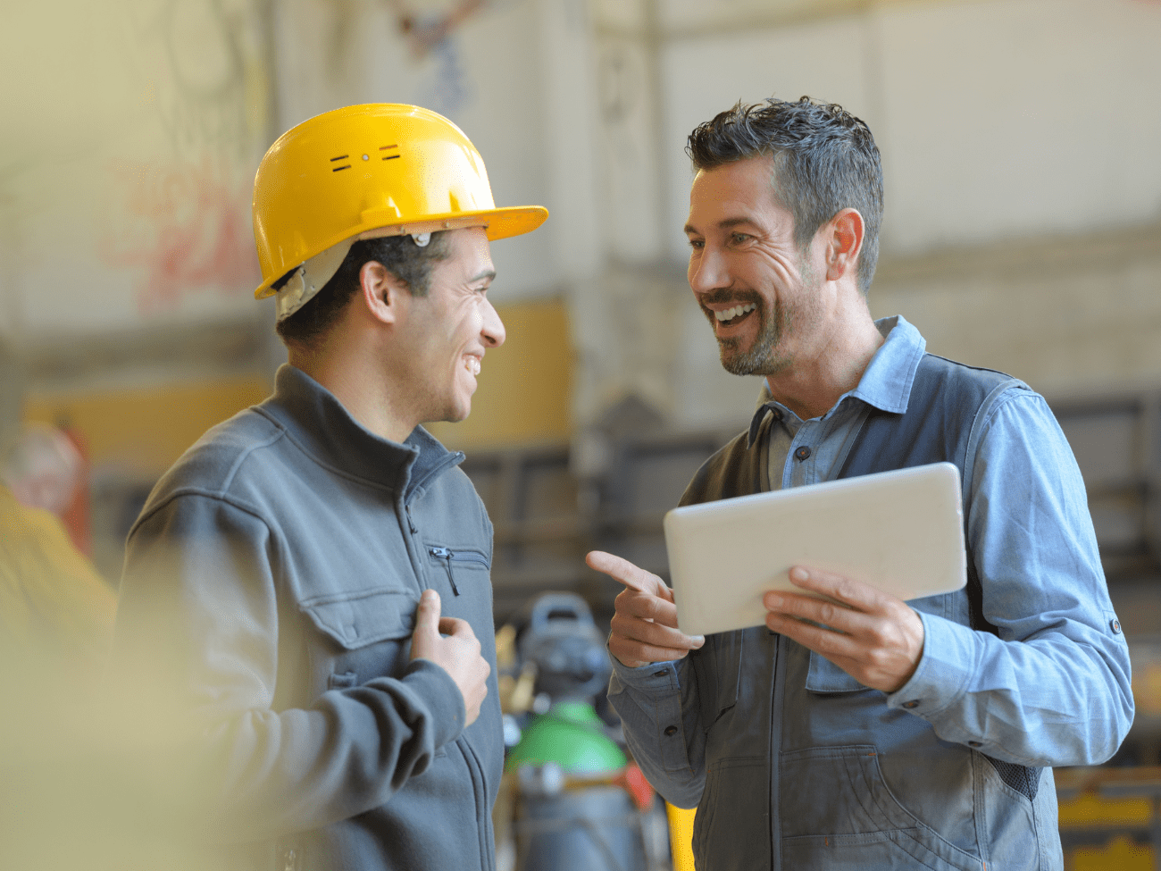 Man In Hard Hat And Man With Tablet Smiling