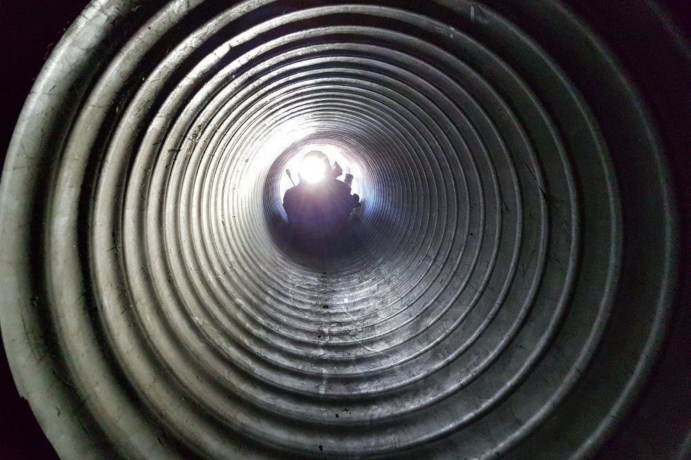 Person With Torch Looking Through Metal Pipe Tube Aspect Ratio 1200 800