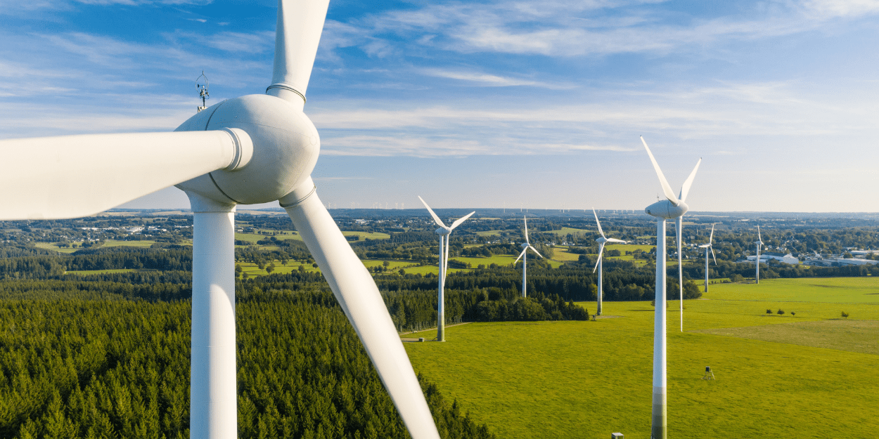 Wind Turbines In A Green Field With Blue Sky Aspect Ratio 1160 580