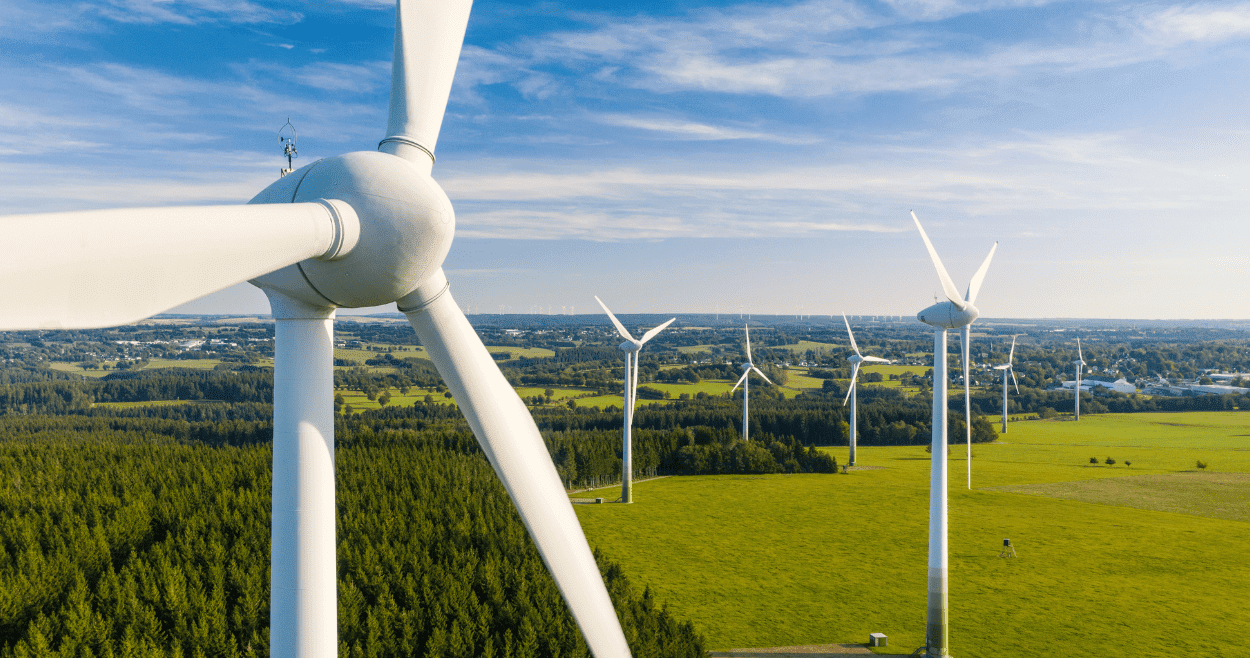 Wind Turbines In A Green Field With Blue Sky Aspect Ratio 760 400