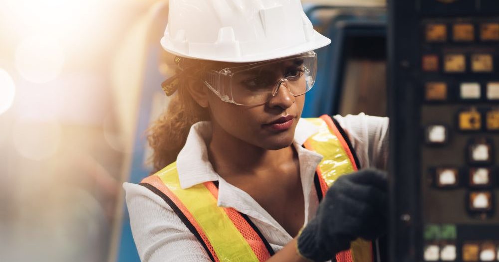 A Woman In A Hard Hat And Safety Glasses Working On A Machine Aspect Ratio 760 400