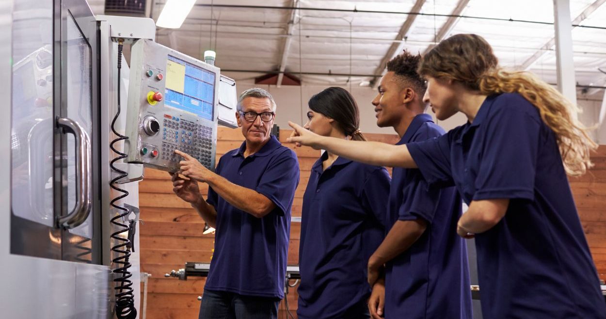 A Group Of Young People Working On A Machine In A Factory Aspect Ratio 760 400