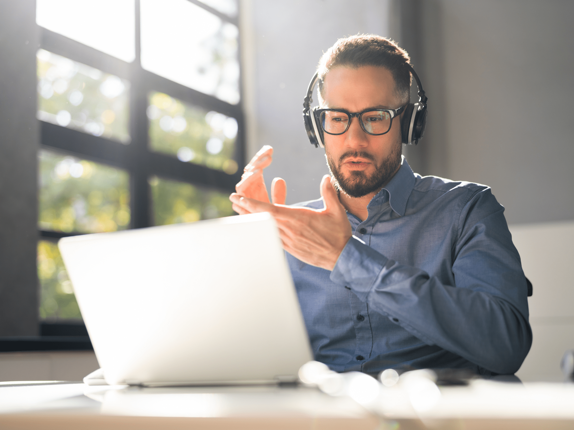 Man With Glasses And Headphones Sitting In Front Of A Laptop